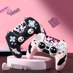 two black and white video game controllers sitting on top of a wooden table next to a laptop