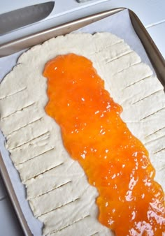 an uncooked pastry with orange icing on it