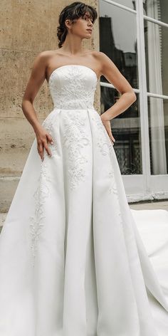 a woman in a white wedding dress posing for the camera with her hands on her hips