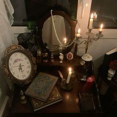 a table with a mirror, clock and candles on it