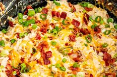 a casserole dish with cheese, bacon and green onions on it's side