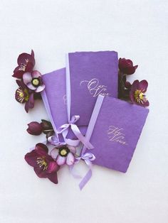 three purple wedding guest books with ribbons and flowers on white background, close up view