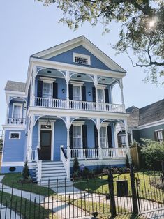 a blue house with white balconies on the front and second story porches