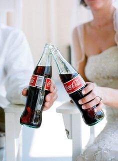 a bride and groom holding up two coca cola bottles