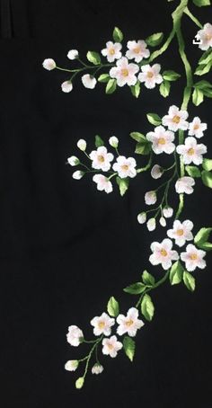 a black shirt with white flowers and green leaves on the chest, embroidered onto it