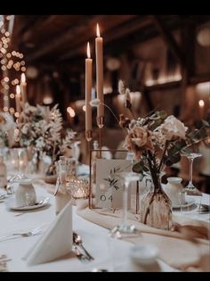 the table is set with candles and flowers in vases, plates and silverware