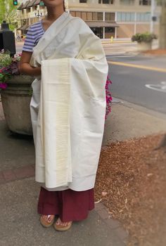 a woman is standing on the sidewalk wearing a white sari and holding a potted plant