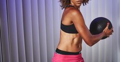 a woman holding a medicine ball in her right hand