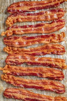 bacon strips are lined up on a baking sheet