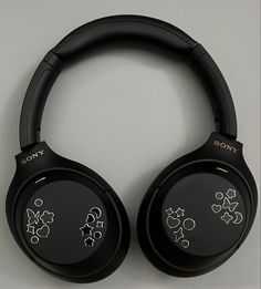 two black headphones with designs on them sitting next to each other in front of a white wall