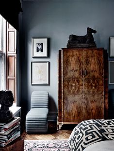 a bedroom with blue walls and an armoire in front of the bed is filled with books