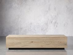 a wooden box sitting on top of a floor next to a concrete wall with a plant in it