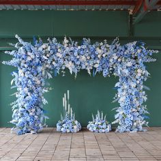 blue and white flowers are arranged in the shape of an arch on a tiled floor