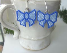 "Be the present with these blue ribbon bows on each side of your face! These adorable blue bows with sparkling darker blue accents are wonderful gifts for any occasion. Exciting and trendy, these earrings will enhance any outfit and will bring many compliments. These earrings are so light that they dance and sparkle with every move you make. Handmade with tiny Miyuki Delica beads they are as unique as they are cute. The sterling silver lever back closures mean you don't have to worry about them slipping out of your earlobe. The dangle's length and the bow's width are close to 1\". AND they are available in several solid colors." Light Blue Beaded Earrings With Ear Wire As Gift, Light Blue Beaded Earrings Gift, Light Blue Beaded Earrings As Gift, Handmade Light Blue Beaded Earrings For Gift, Cute Light Blue Earrings For Gift, Cute Light Blue Earrings Gift, Miyuki Delica Beads, Cute Gifts For Her, Beaded Earrings Diy