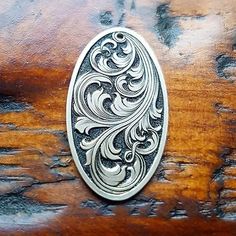 an ornate silver broochle sitting on top of a piece of wooden tablecloth