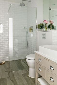 a bathroom with white tile and wood flooring