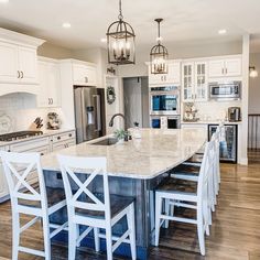 a large kitchen with white cabinets and marble counter tops