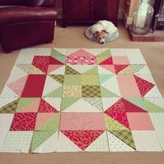 a dog laying on the floor next to a quilt