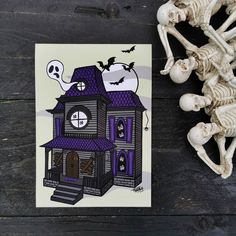 a halloween card with a creepy house and skeleton on the front, sitting next to it