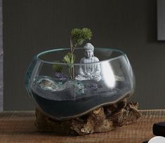 there is a glass bowl with water and plants in it on top of a table