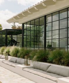 an outdoor seating area with large windows and plants on the outside, along side it