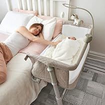 a woman laying on top of a bed next to a baby in a crib