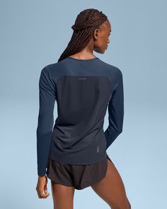 a woman in black shorts and a blue shirt is looking down at the back of her body