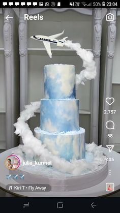 a blue and white wedding cake with an airplane flying over it on top of a table