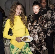 three people standing next to each other holding plates