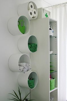 a white shelf filled with green items next to a window