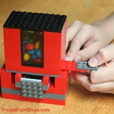 a person holding a remote control in front of a small lego box with candy inside