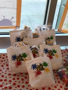 six bags with paint splatters on them sitting on a table next to a window