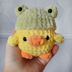 a hand holding a small stuffed animal in the shape of a duck with a hat on it's head