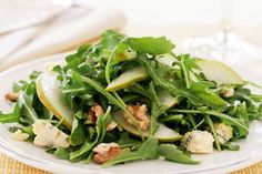 a white plate topped with green salad and apple slices on top of lettuce