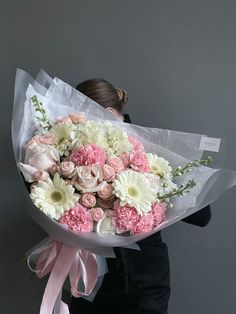 a woman holding a large bouquet of flowers in her hands and wearing a black jacket