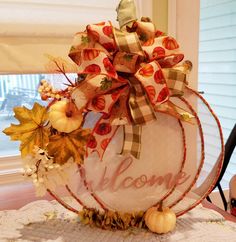 a welcome sign with fall leaves and gourds in front of a window sill