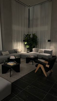 a living room filled with lots of furniture and a large window covered in sheer curtains