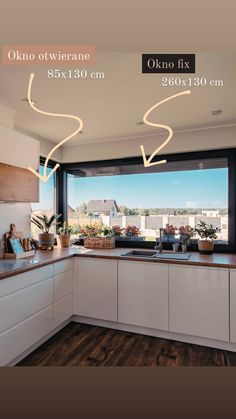 a kitchen with white cabinets and wooden flooring next to a large window overlooking the ocean