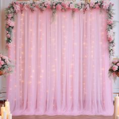 the backdrop is decorated with pink flowers and white candles for an elegant wedding or special event