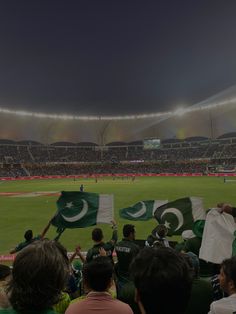 a group of people standing on top of a baseball field holding pakistan and pakistan flags