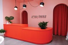 an orange counter with plants on it in front of a pink wall and red curtains