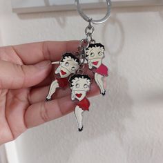 a person holding two key chains with cartoon characters on them, in front of a white background