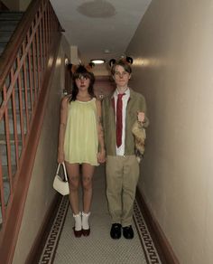 two people dressed in costumes are walking down the hallway