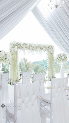 the chairs are covered with white cloths and flower arrangements for an outdoor wedding ceremony