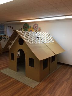 a cardboard house made to look like it has a roof that looks like a doghouse