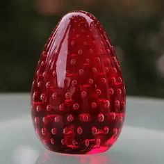 a red glass vase sitting on top of a table