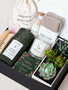 an open gift box containing candles, soaps, and other personal care items with succulents