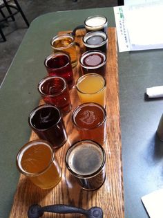 a wooden table topped with lots of glasses filled with different types of liquid and beverages