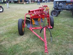 an old tractor is parked on the grass near other antique tractors and people in the background