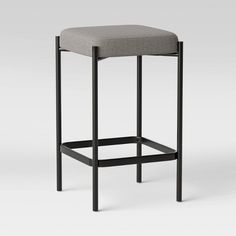 the backless stool is made from black metal and has a gray upholstered seat